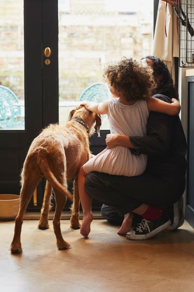 Mother and young daughter with dog looking out of kitchen window_resize