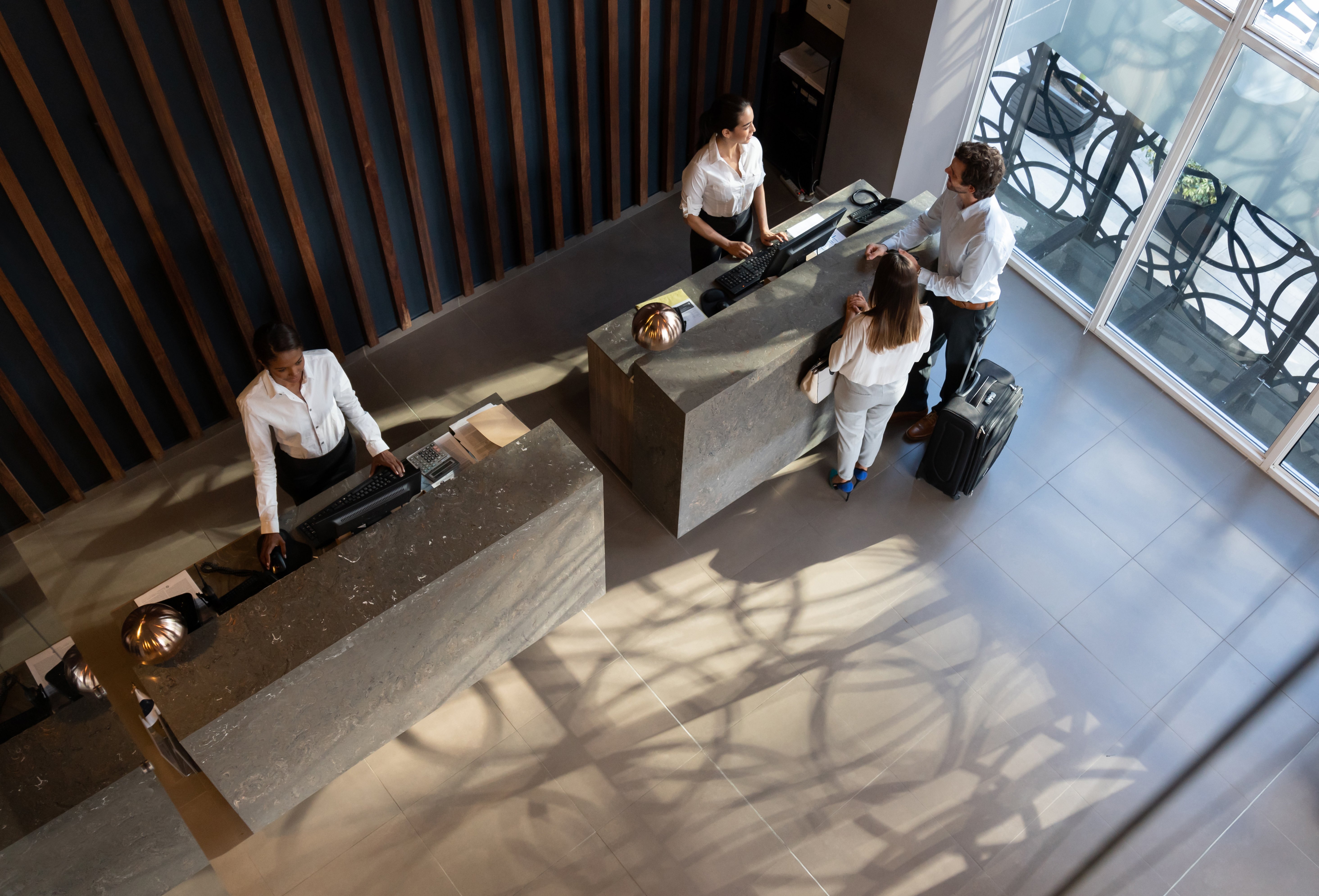 Young business couple checking in at hotel and beautiful receptionist helping them